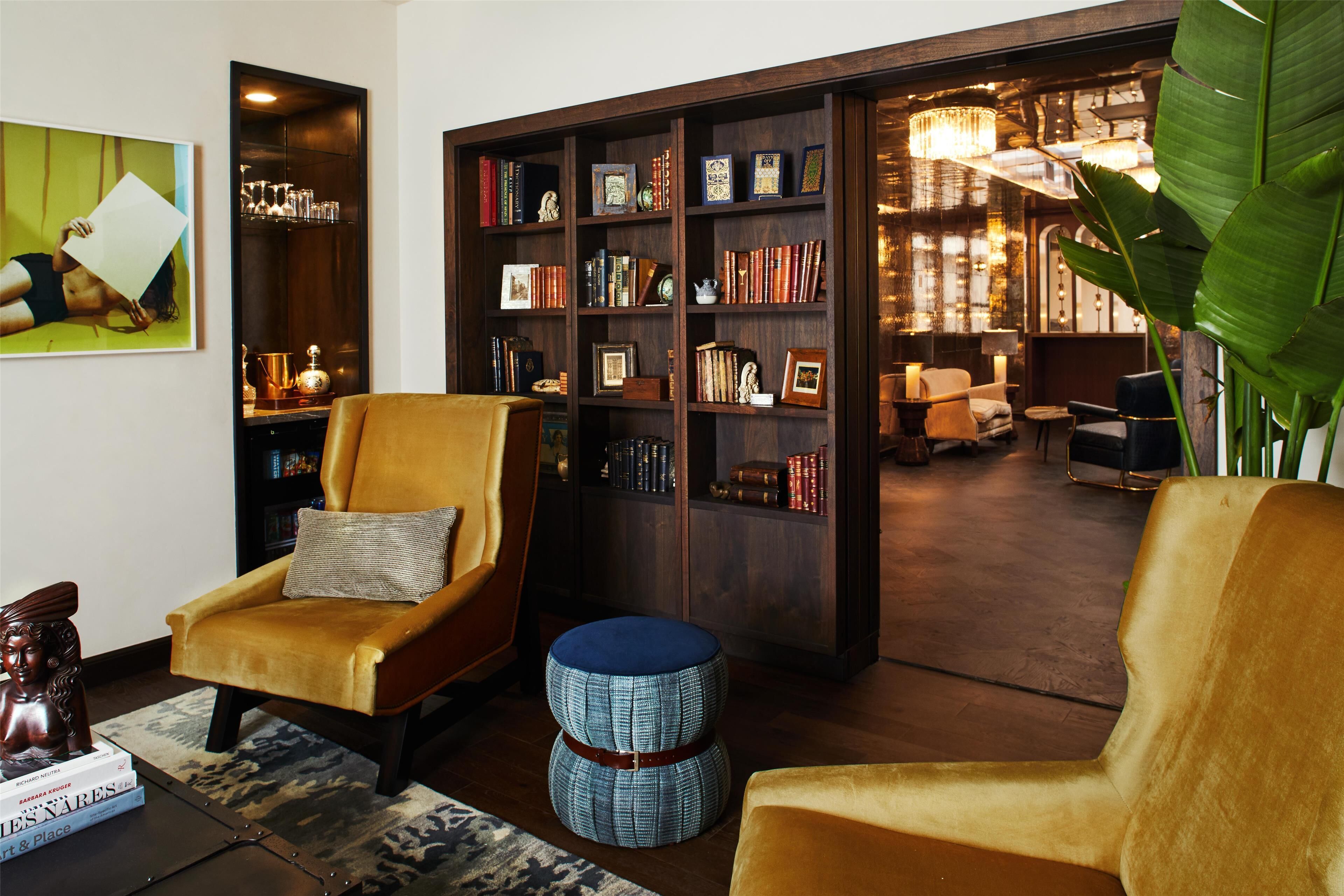 A cozy reading nook with a plush armchair, a small ottoman, and a bookshelf filled with books and decorative items.