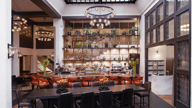 A bar area with a long counter, multiple seating options, and a variety of bottles and glasses. - Hotel Figueroa, Unbound Collection by Hyatt (Los Angeles)