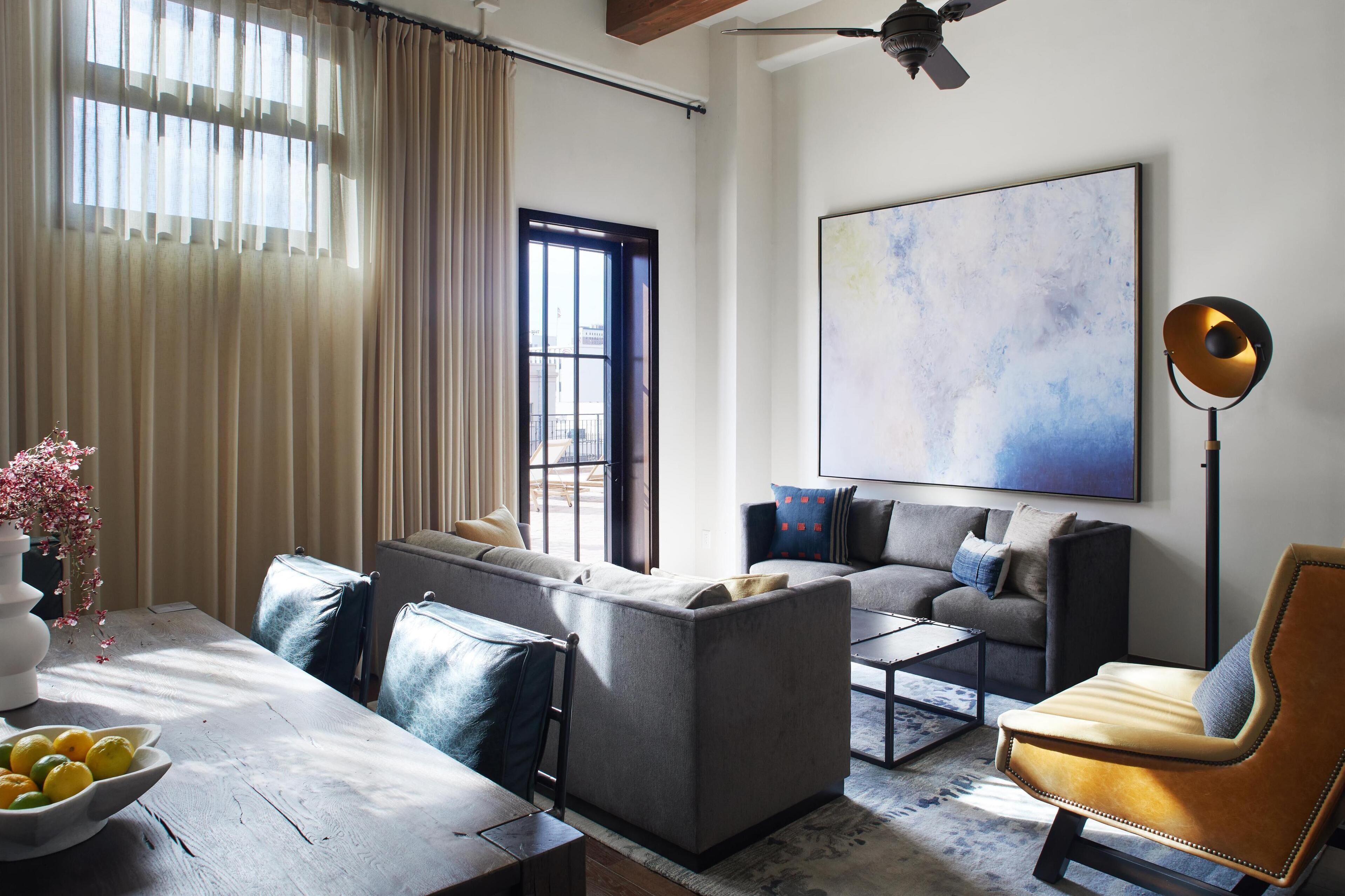 Un salon moderne avec un ensemble de canapés, une table basse et un grand tableau abstrait accroché au mur.