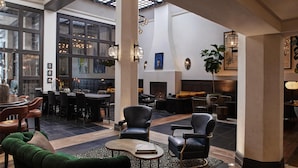 A spacious lobby with a fireplace, seating area, and a bar. - Hotel Figueroa, Unbound Collection by Hyatt (Los Angeles)