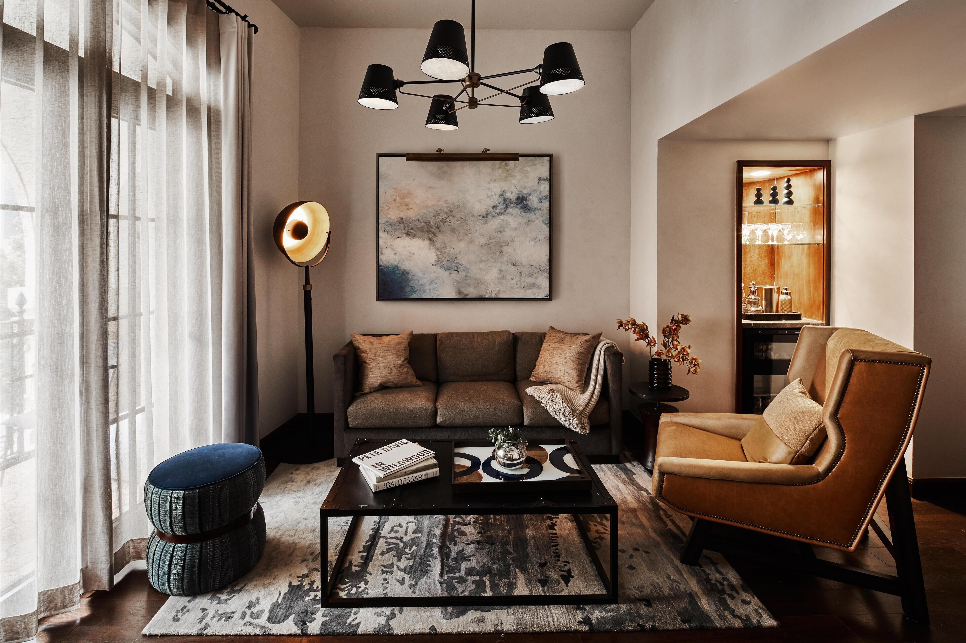 A modern living room with a sofa, armchair, coffee table, and a large abstract painting.