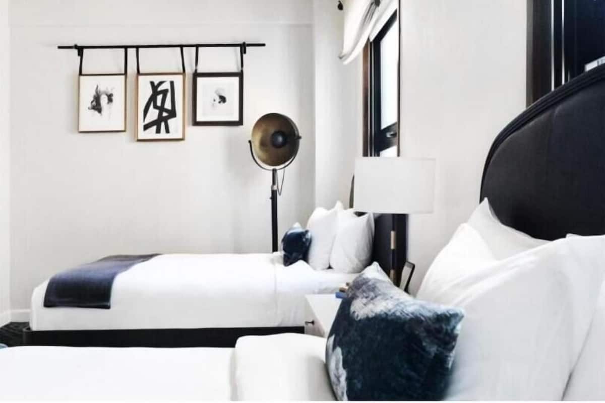 Ein Hotelzimmer mit zwei Betten, einem Nachttisch, einer Lampe und Bildern an der Wand.