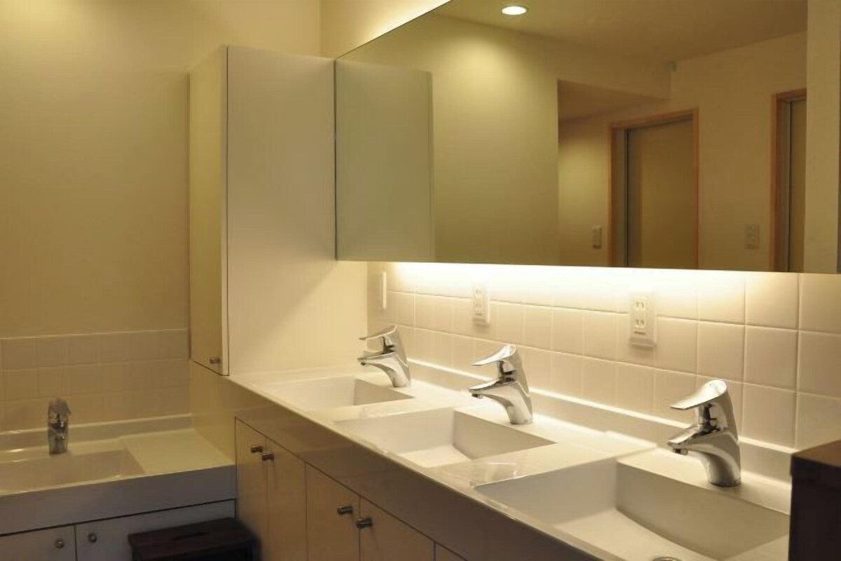 A modern bathroom with three sinks, a large mirror, and a cabinet.