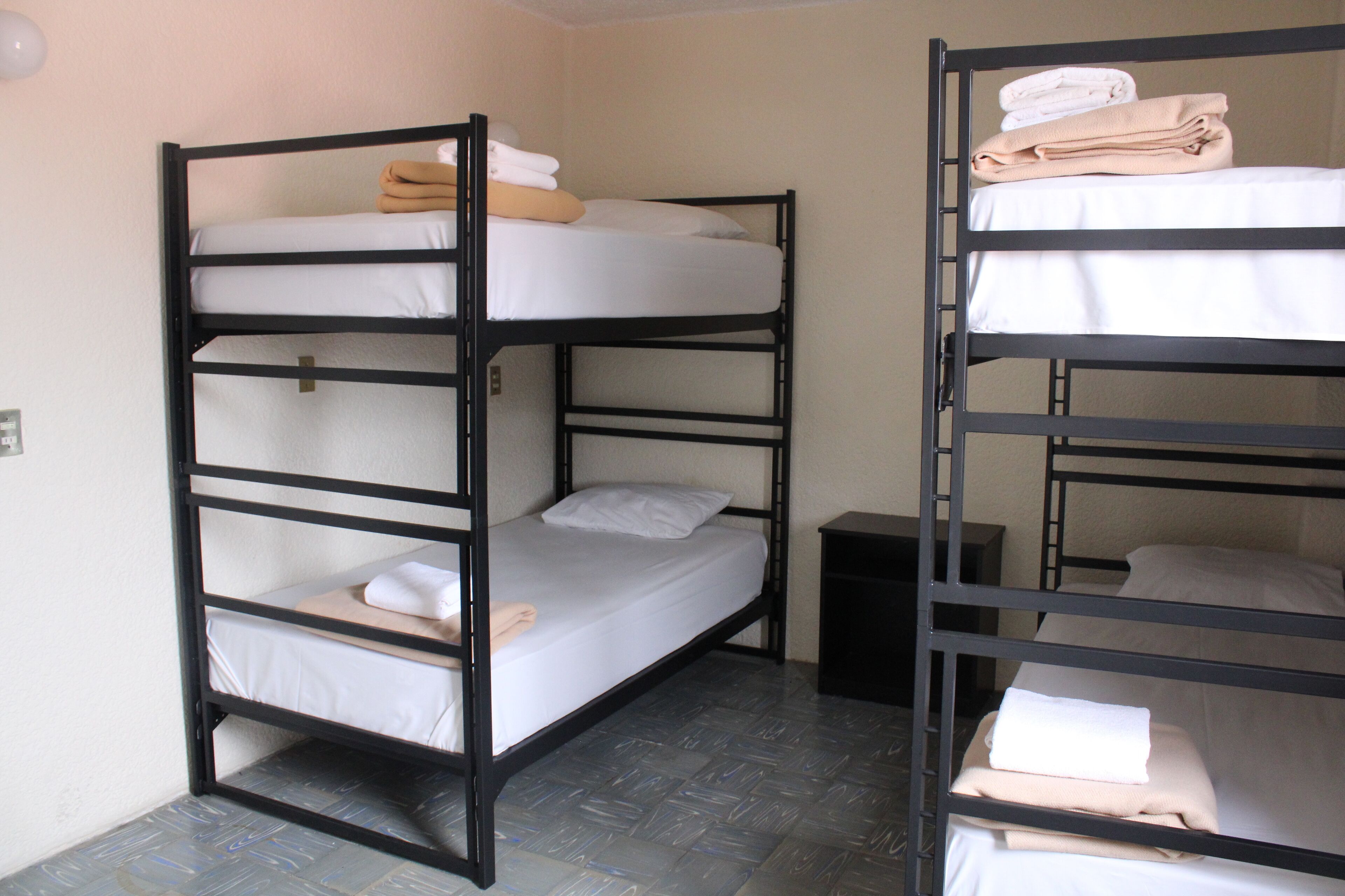 A bunk bed room with two beds, each with a mattress and pillows.