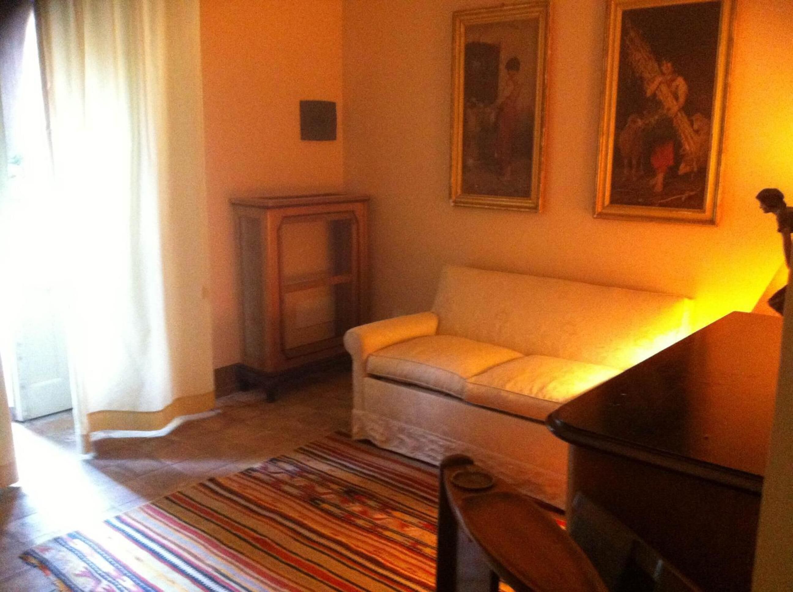 Una sala de estar con un sofá, un mueble de madera pequeño y una alfombra colorida a rayas.