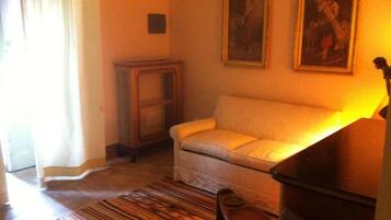 Una sala de estar con un sofá, un mueble de madera pequeño y una alfombra colorida a rayas.