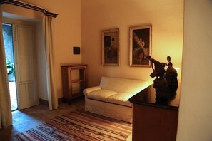 A room with a white sofa, a patterned rug, and two framed paintings on the wall. - Casa la Carrubbazza (San Gregorio di Catania)