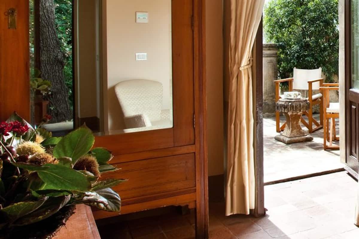 Un dormitorio con cama, mesita de noche, lámpara y vistas al exterior.