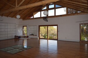 Una habitación amplia con suelos de madera, ventanas grandes y techo alto.