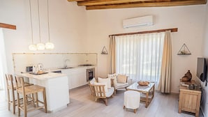 A modern kitchen with a central island, wooden chairs, a dining table, and a TV on a wooden cabinet. - Las Dalias (Las Rosas)