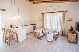 Una cocina moderna con una isla central, sillas de madera, una mesa de comedor y un televisor sobre un mueble de madera.