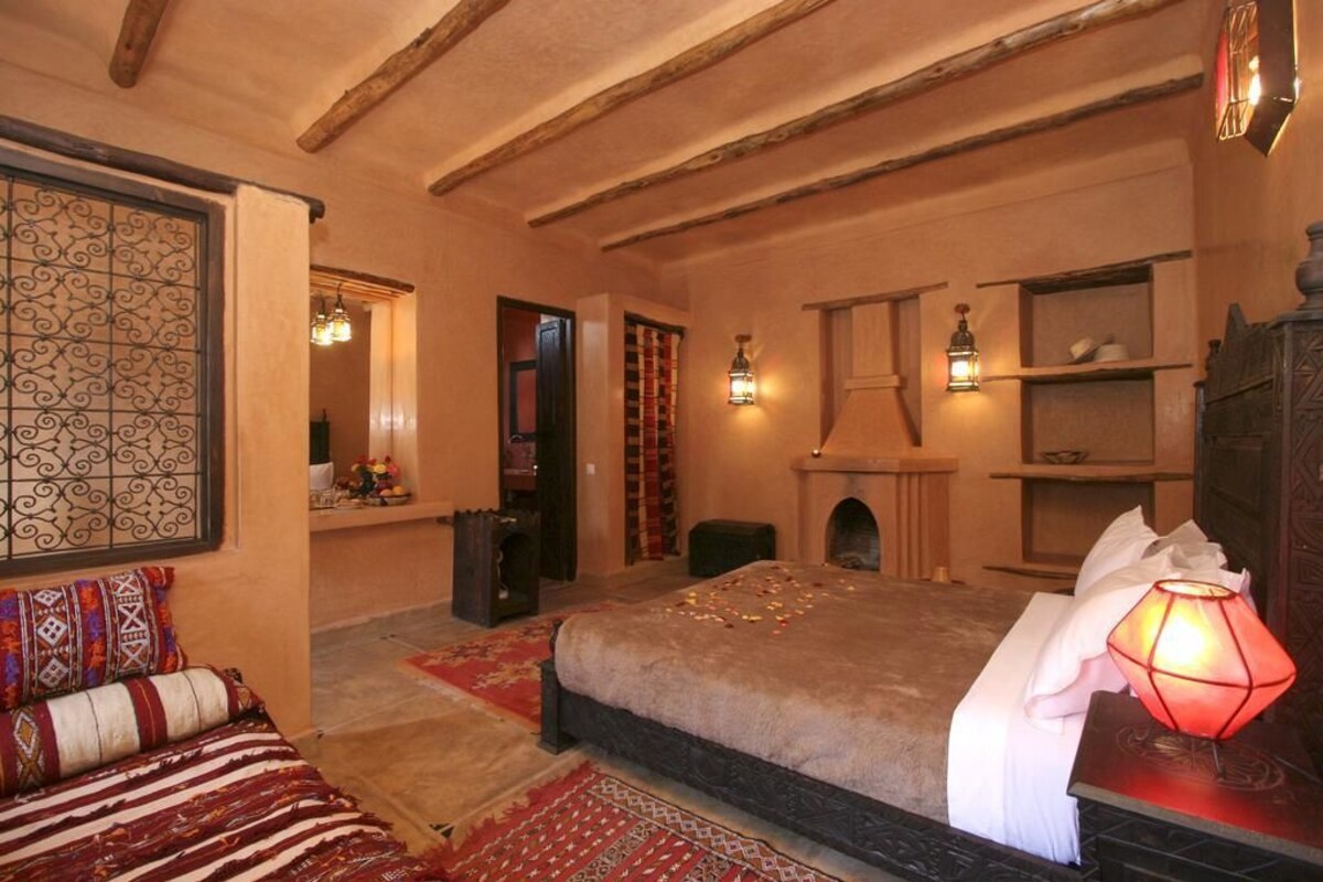 A cozy bedroom with a large bed, a fireplace, and a decorative wall.