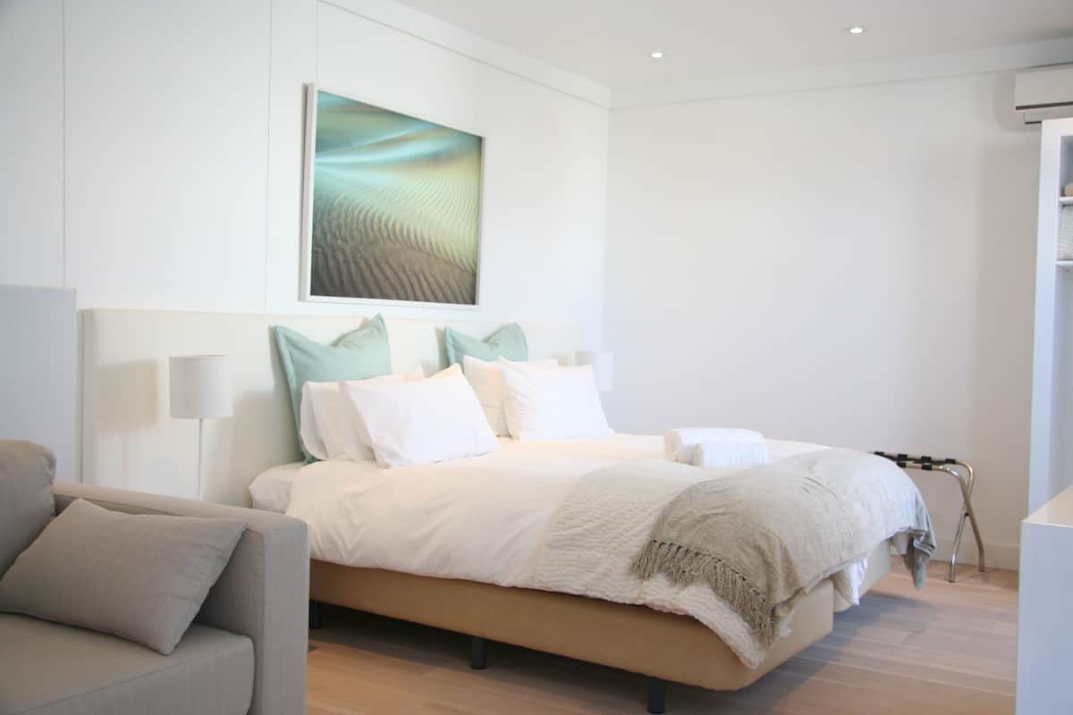 Ein modernes Schlafzimmer mit einem Bett, einer Couch und einem Wandbild.