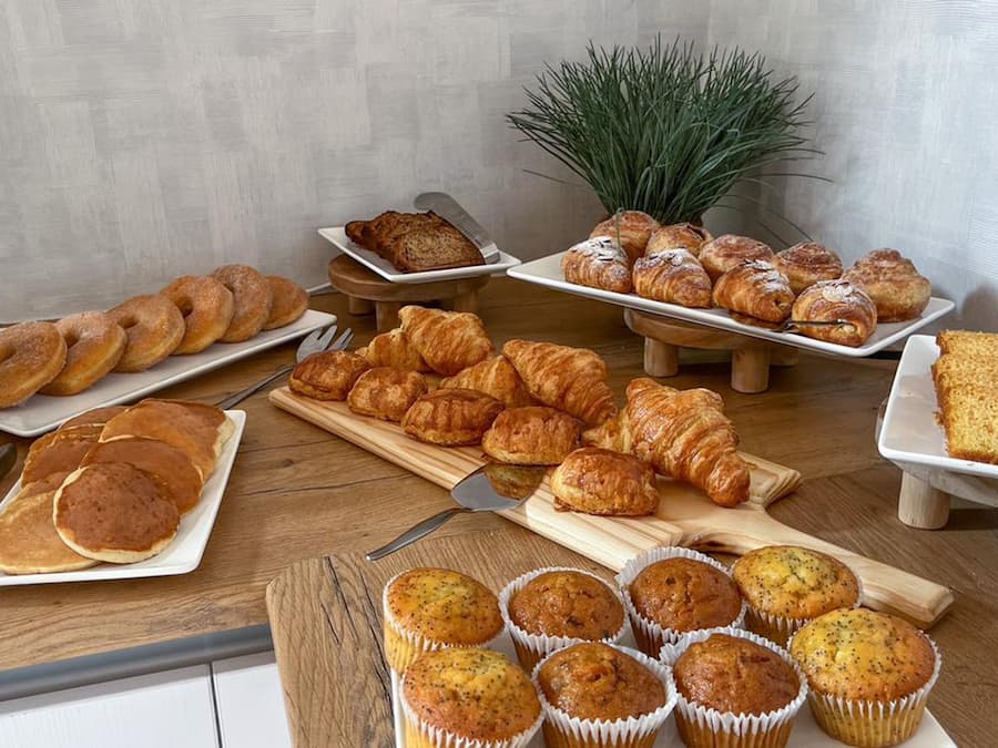 A breakfast buffet with various pastries, muffins, and a cake.