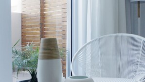 Een modern interieur met een ronde witte tafel, een witte stoel en een raam met dunne gordijnen.