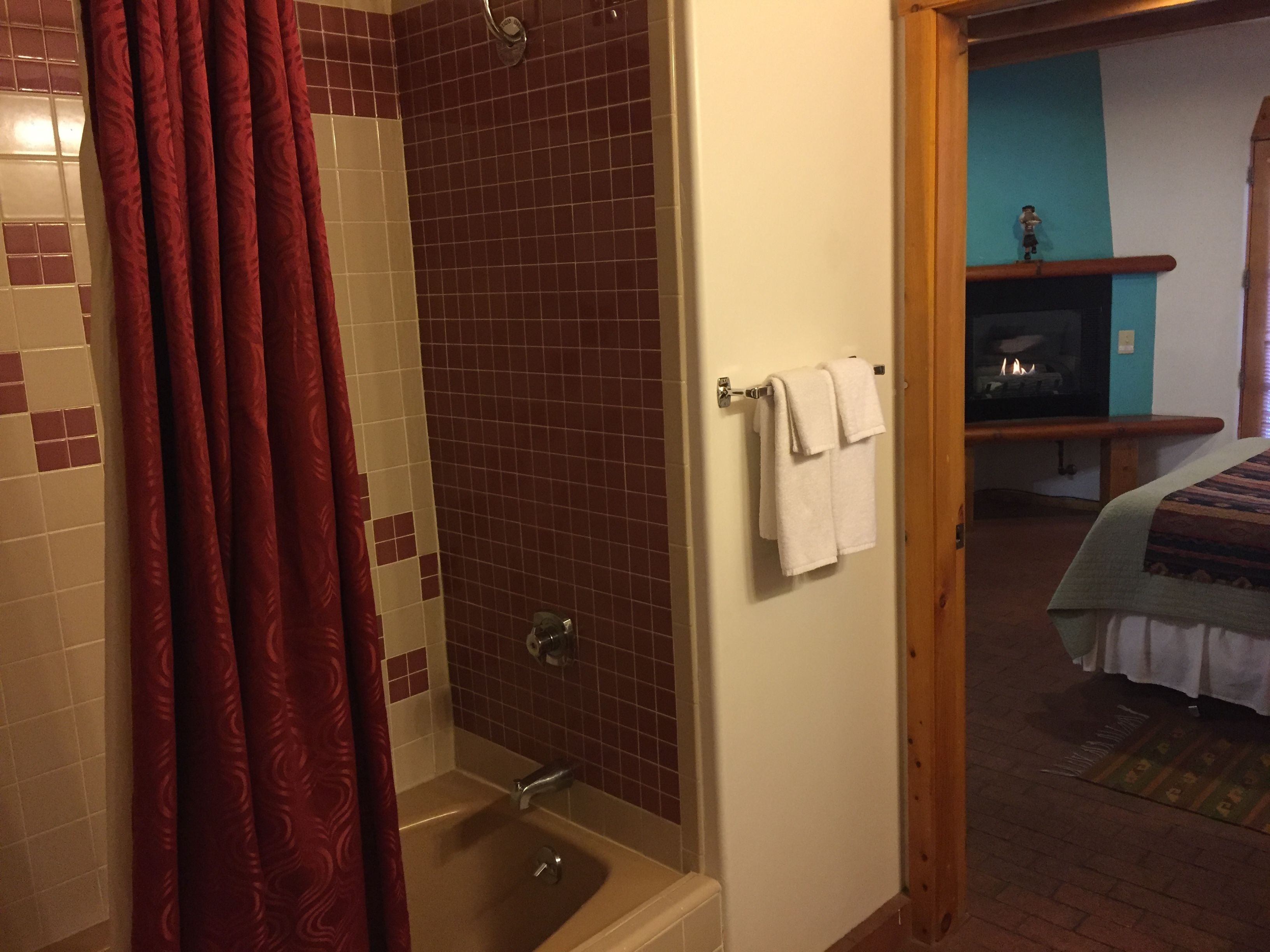 Un baño con bañera, cortina de ducha y un perchero con toallas.