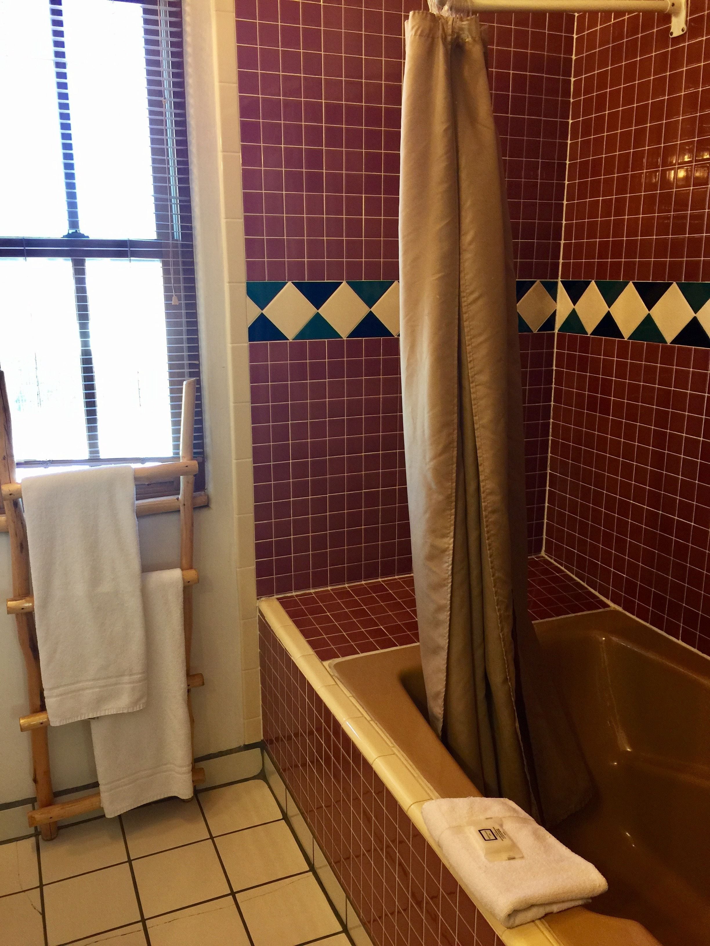 A bathroom with a bathtub, a shower curtain, and a towel rack with towels.