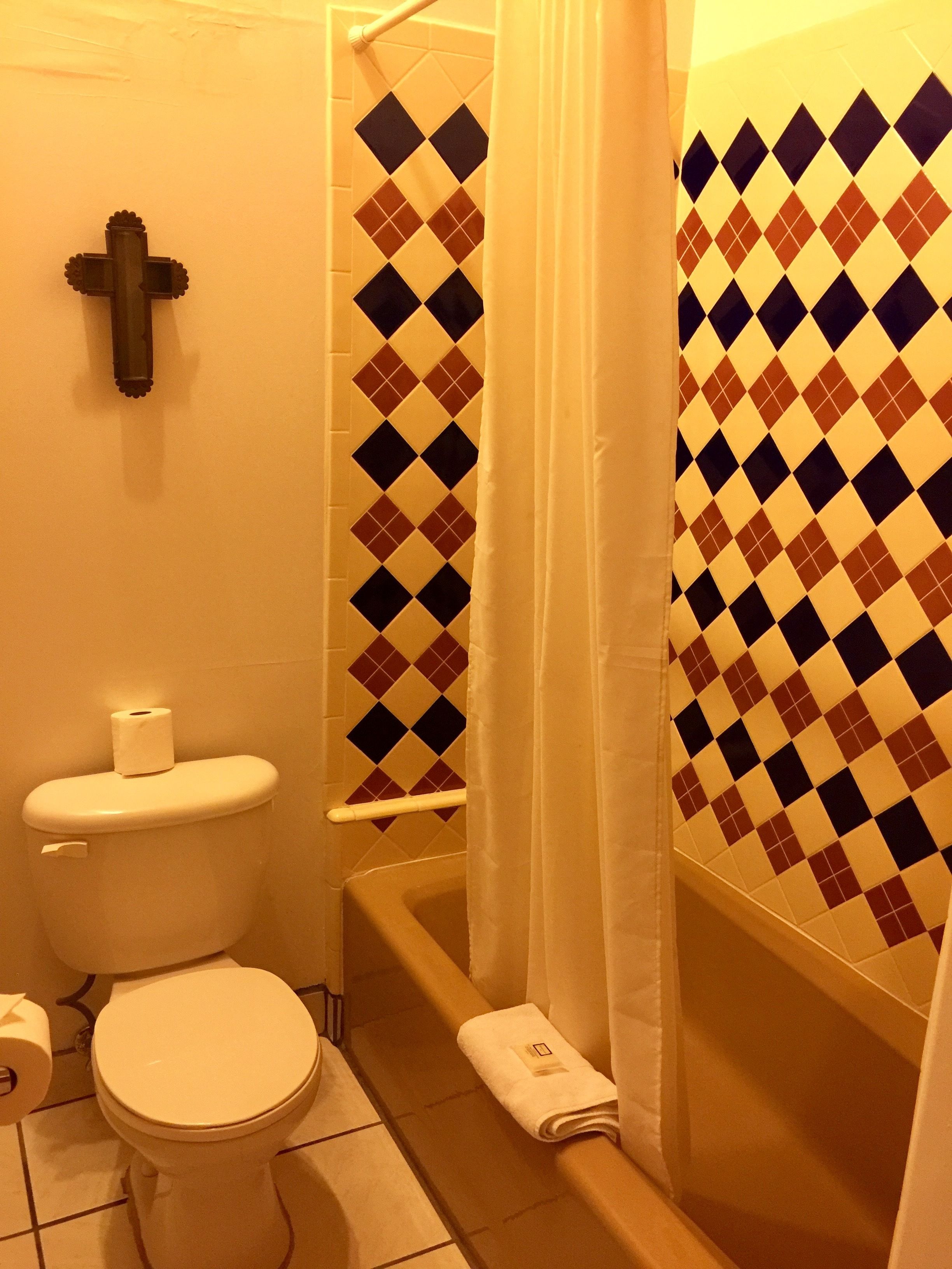 Une salle de bain avec des toilettes, un rideau de douche et un mur décoré d’un motif.