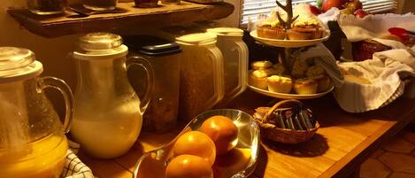 A kitchen counter with various food items, including a pitcher, a glass jar, and a plate of oranges.