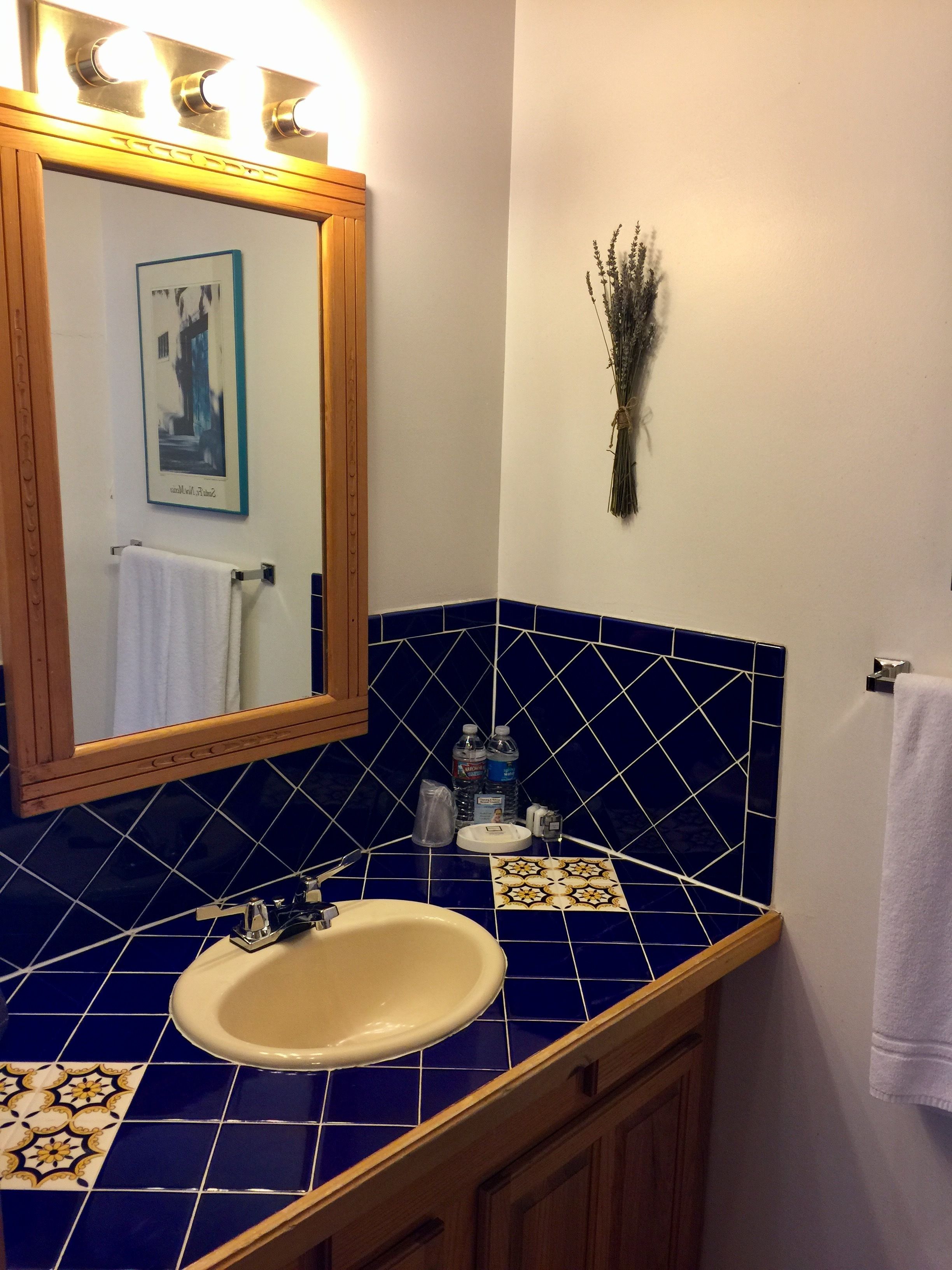 Une salle de bain avec un lavabo, un miroir et des murs recouverts de carreaux bleus.