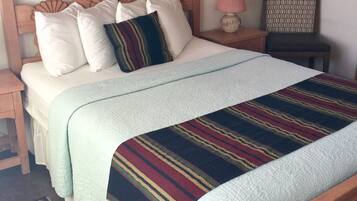 A neatly made bed with a striped blanket, a wooden headboard, and a nightstand with a lamp.