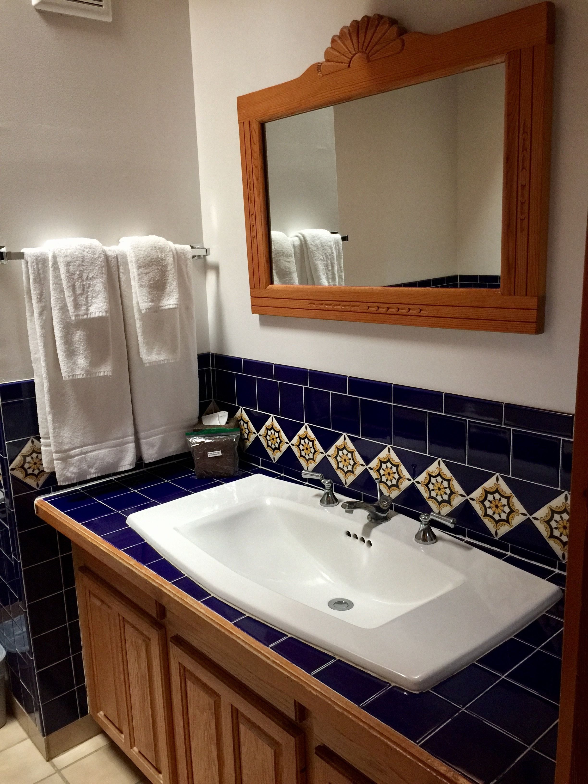 A bathroom with a white sink, wooden cabinets, and blue-tiled walls.