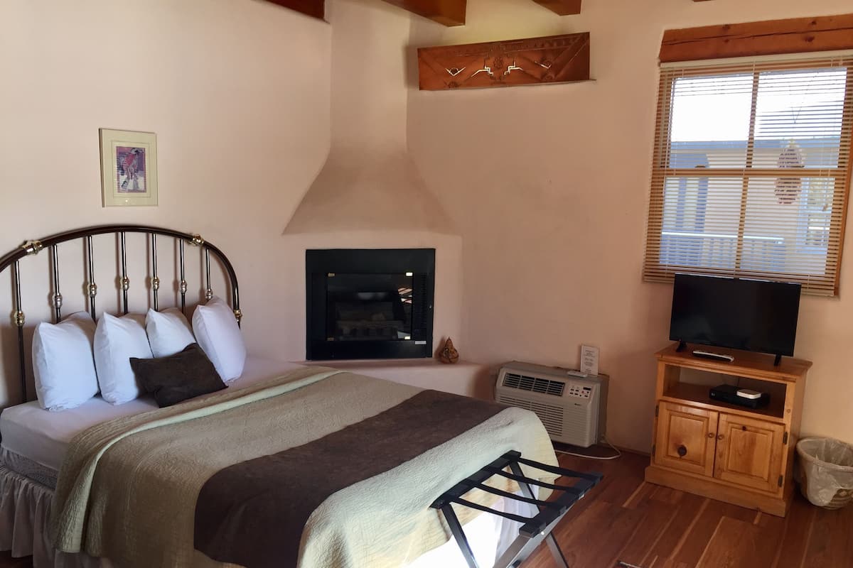 Quarto com cama, lareira, televisão e um armário de madeira.