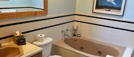 A bathroom with a bathtub, toilet, sink, and a framed picture on the wall.