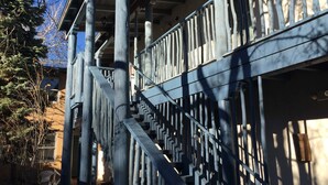 A wooden staircase with a geometric railing design, leading to a building with a sloped roof. - Guadalupe Inn (Santa Fe)