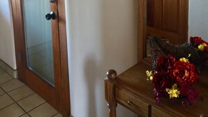 A room with a wooden door marked with the number 11, a glass door, and a wooden table with a floral arrangement. - Guadalupe Inn (Santa Fe)