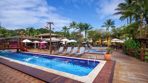 Un área de piscina con varias piscinas, sillas de descanso y sombrillas.