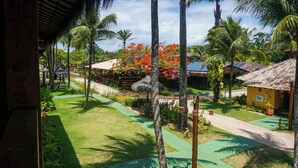 Un resort tropical con cabañas de techo de paja, palmeras y un jardín bien cuidado.