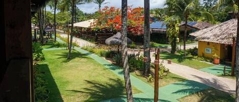 A tropical resort with thatched-roof huts, palm trees, and a well-maintained garden.