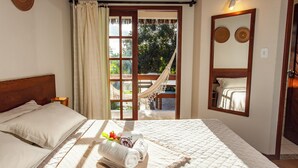 Un dormitorio con una cama, una hamaca, un ventanal grande y un espejo.
