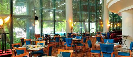 A spacious restaurant with high ceilings, large windows, and a variety of seating arrangements.