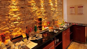 Zona de bufé con pared de piedra de fondo, diferentes opciones de comida y condimentos.