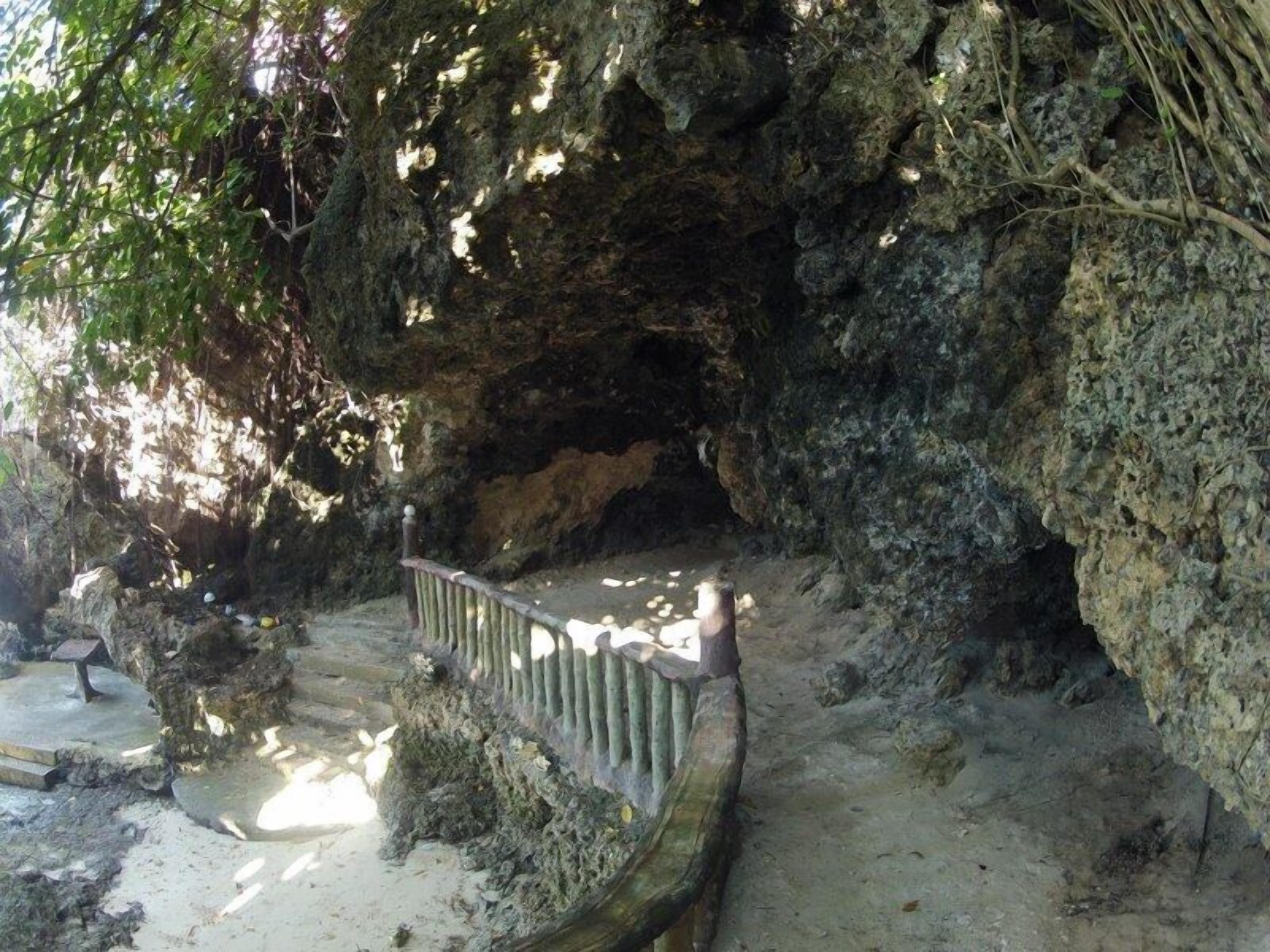 A natural rock formation with a wooden staircase leading up to a cave entrance.
