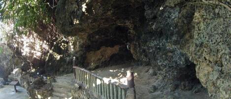 A natural rock formation with a wooden staircase leading up to a cave entrance.