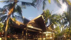 A modern building with a sloped roof and multiple levels, surrounded by palm trees. - Santiago Bay Garden & Resort (San Francisco)