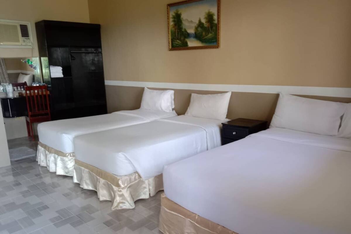 Ein Hotelzimmer mit zwei Betten, einem kleinen Schreibtisch, einem Stuhl und einem Bild an der Wand.