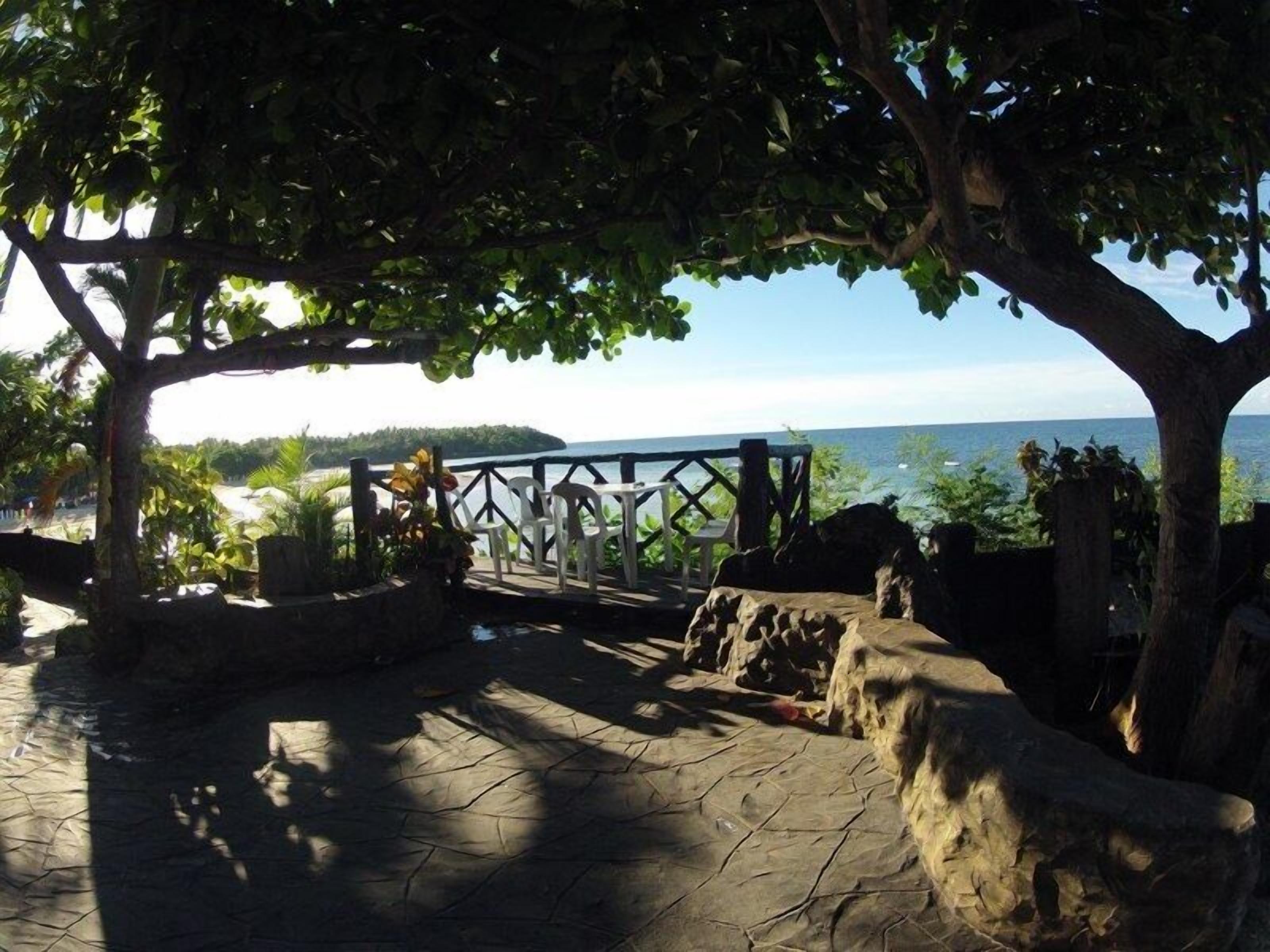 A stone patio with a wooden fence overlooking a body of water.