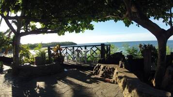 A stone patio with a wooden fence overlooking a body of water.
