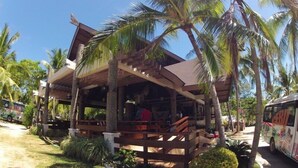 A wooden structure with a covered porch, surrounded by palm trees and greenery. - Santiago Bay Garden & Resort (San Francisco)