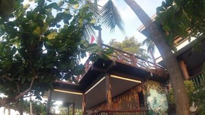A wooden structure with a balcony, surrounded by lush greenery and palm trees. - Santiago Bay Garden & Resort (San Francisco)