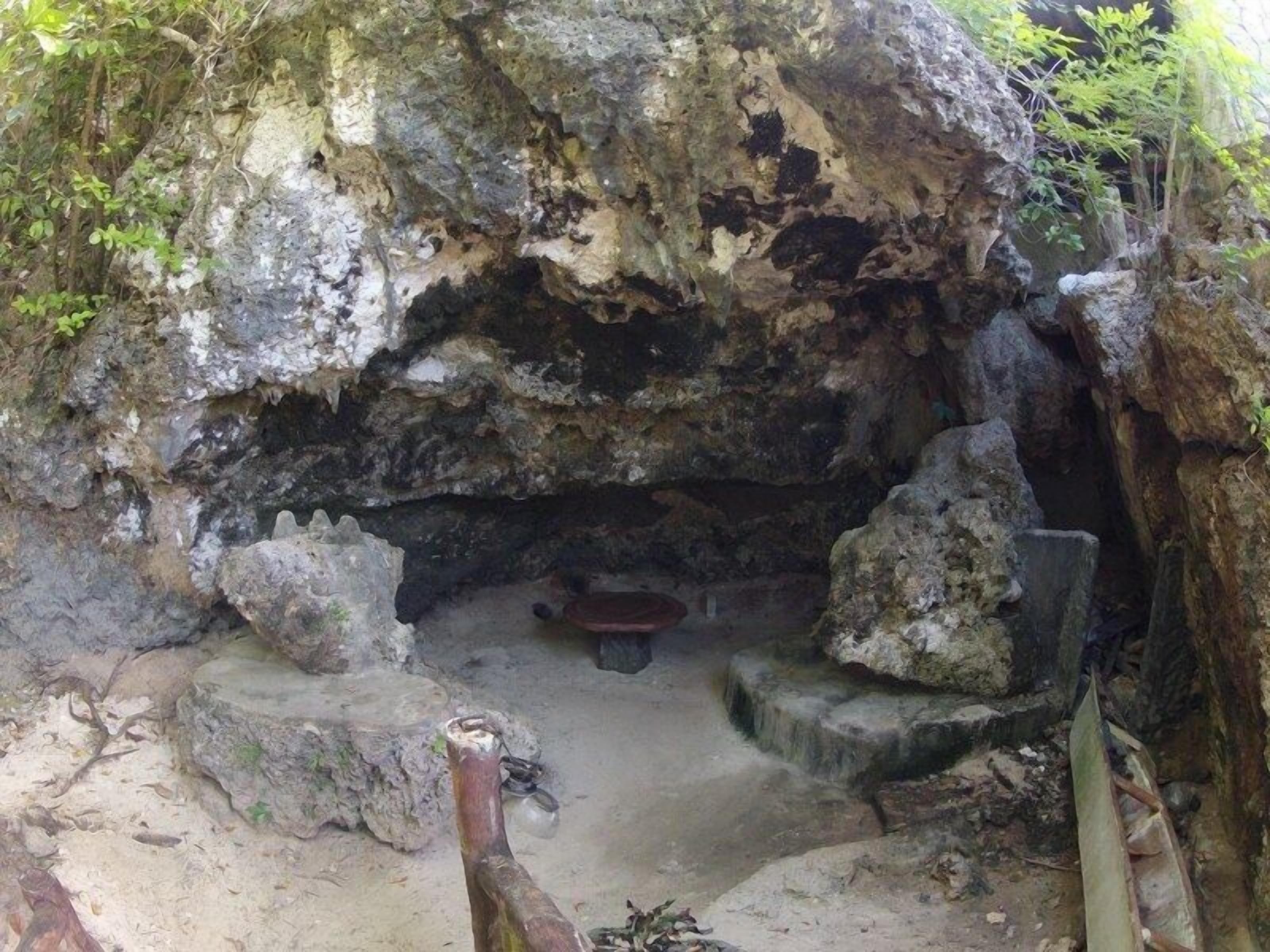 La entrada de una cueva con un banco pequeño y una estructura de piedra en su interior.