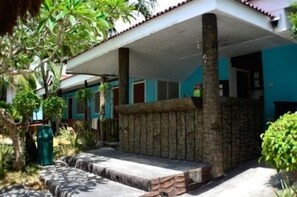 Un espacio al aire libre cubierto con un muro de piedra, un banco de hormigón y una pequeña fuente.