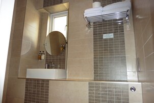 Un baño con lavamanos, espejo y toallero.