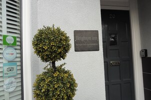 Una puerta con un cartel que dice "Brighton Inn Boutique Guest Accommodation" y una placa con el número "20".