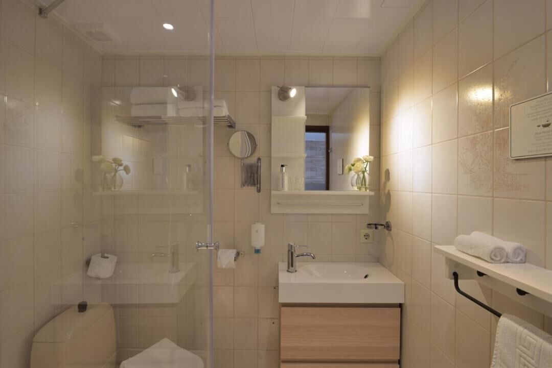 A modern bathroom with a glass shower enclosure, a sink, and a vanity with a mirror.