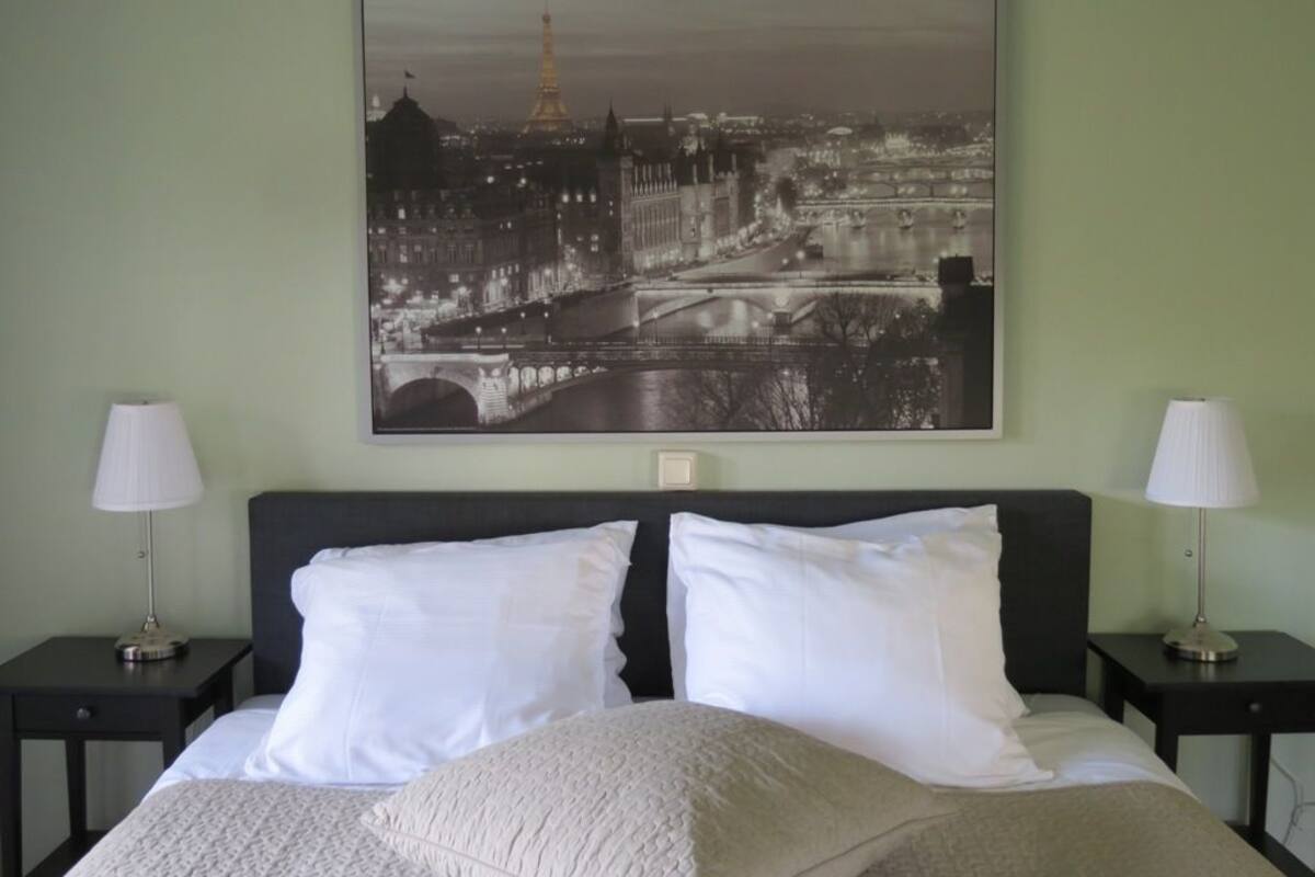 Ein Hotelzimmer mit einem Bett, zwei Nachttischen und einem großen Schwarz-Weiß-Stadtbild an der Wand.